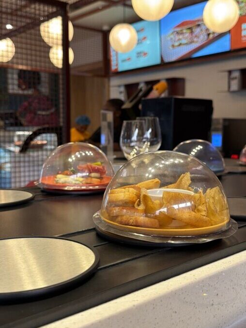 Plates moving on a conveyor belt dining system at Biscuit Bone & Co, the first conveyor belt restaurant in Nigeria