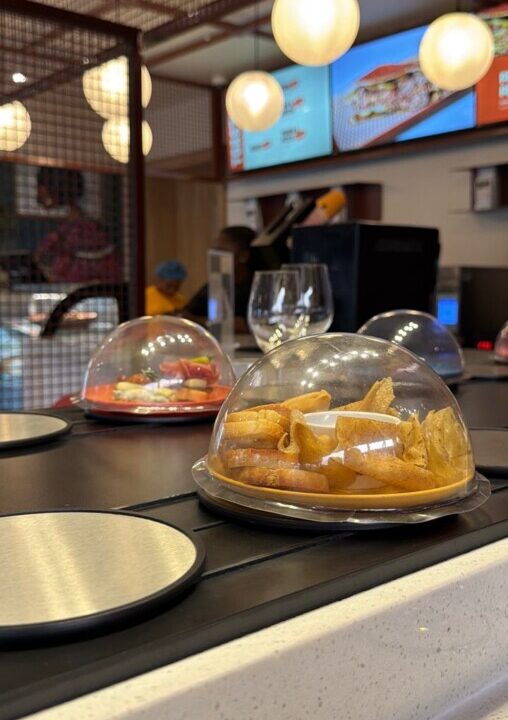 Plates moving on a conveyor belt dining system at Biscuit Bone & Co, the first conveyor belt restaurant in Nigeria